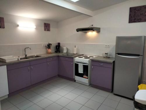eine Küche mit lila Schränken, einer Spüle und einem Herd in der Unterkunft Gîte de groupe 2 à 12 personnes in Guillon
