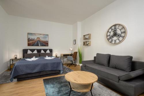1 dormitorio con cama, sofá y reloj en SweetHome - Zentral - Küche & Parkplatz, WiFi en Halle an der Saale