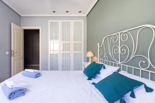 a bedroom with a large white bed with blue pillows at Home2Book Comfy Apt Puertito de Güímar, Pool in Puertito de Güímar