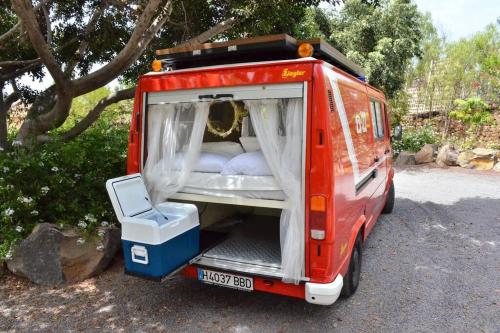 a red van with its back open with a bed at Conny, a Mercedes Firefighter Camper Van in Los Cristianos