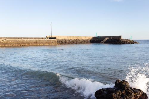 a body of water with a pier and waves at Home2Book Comfy Apt Puertito de Güímar, Pool in Puertito de Güímar