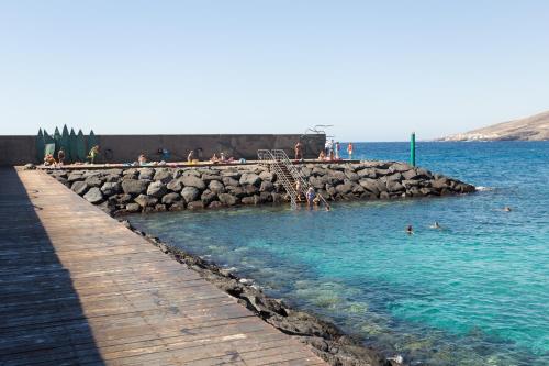 a beach with people swimming in the water at Home2Book Comfy Apt Puertito de Güímar, Pool in Puertito de Güímar