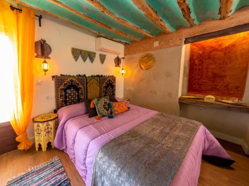 ein Schlafzimmer mit einem Bett mit violetter Bettwäsche und einem Fenster in der Unterkunft Domus Lapidis - Medina in Bogarra