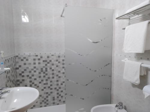 ein weißes Bad mit einem Waschbecken und einer Dusche in der Unterkunft Hostal Los Arcos in Chipiona