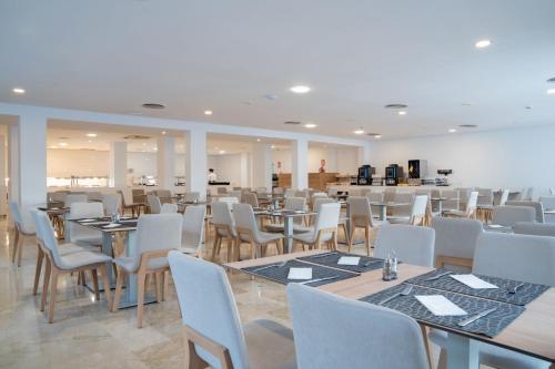 a dining room with tables and white chairs at Aparthotel Caprice Isabel in Cala Bona