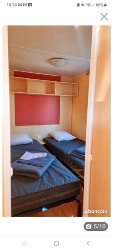 deux lits dans une petite pièce avec dans l'établissement Mobil-home Puy du Fou, à La Boissière-de-Montaigu