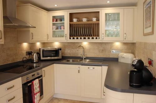 a kitchen with white cabinets and a sink at Poet's Cottage, Steep - Rural Location - Sleeps 6 in Steep