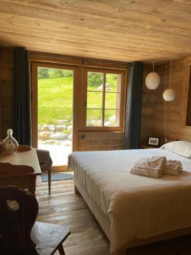 a bedroom with a large bed and a window at Alpen Charme - Chalet d'Hôtes et SPA in Gsteig