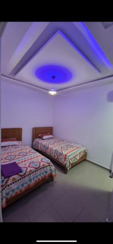 two beds in a room with a blue ceiling at Stylish City Apartment in Monastir