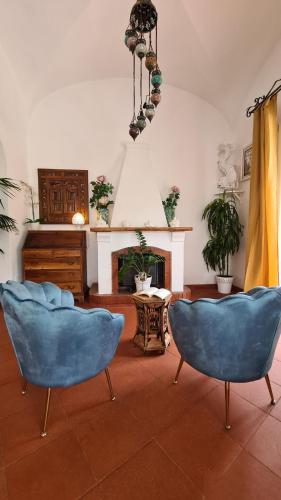 un soggiorno con 2 sedie blu e un camino di Casa Bon Bon a Positano