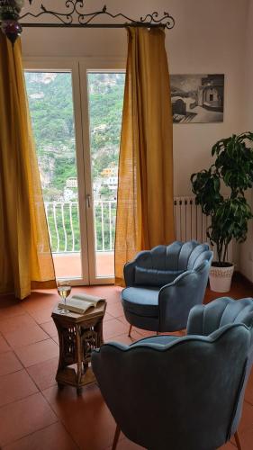 a living room with blue chairs and a large window at Casa Bon Bon in Positano