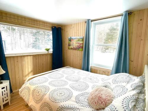 1 dormitorio con 1 cama y 2 ventanas en Chalet Falaise by Chalets NABU en Saint-Alexis-des-Monts