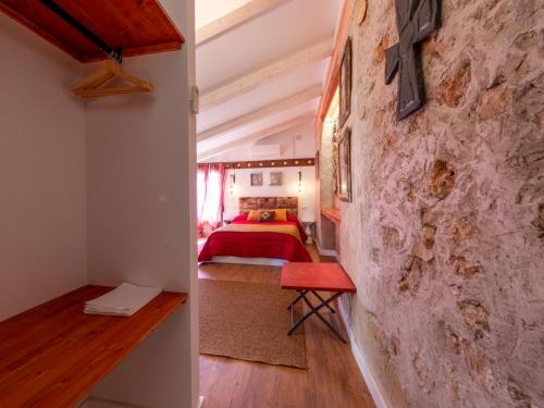 1 dormitorio con cama roja y pared de piedra en Domus Lapidis - Villa, en Bogarra