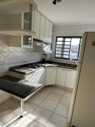 a kitchen with white cabinets and a refrigerator at Apartamento 32 no centro de Águas de São Pedro in Águas de São Pedro