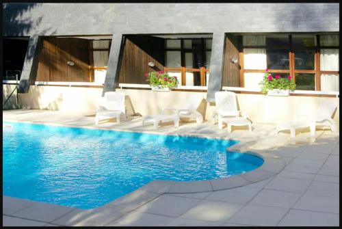 une piscine avec des chaises blanches à côté d'une maison dans l'établissement appartement 6/7 personnes, à Saint-Lary-Soulan