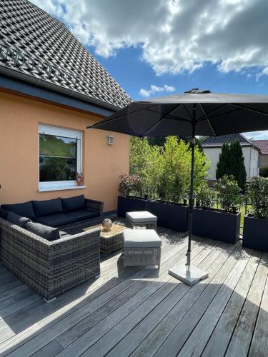 a patio with a couch and an umbrella at Oase der Ruhe 2 in Waldsieversdorf