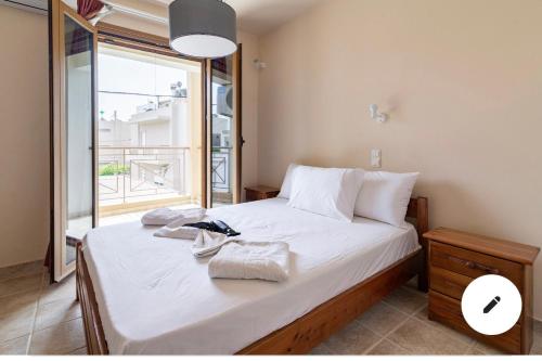 a bedroom with a bed with white sheets and a window at Crown apartments in Agia Pelagia