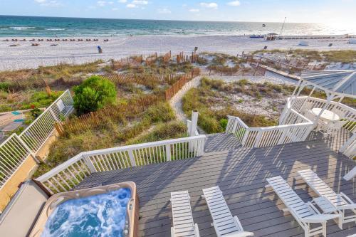 a deck with a hot tub and chairs on the beach at Sandy Feet Retreat in Panama City Beach