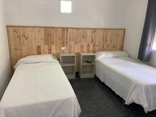 Malvarrosa Beach Rooms في فالنسيا: سريرين في غرفة بجدران خشبية