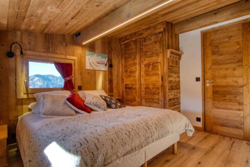 a bedroom with a bed with wooden walls and a window at chalet l'Orignal 145m2, 10pers, pied de piste,SPA in Notre-Dame-de-Bellecombe