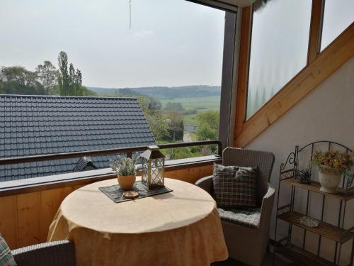 einen Tisch und Stühle auf einem Balkon mit einem großen Fenster in der Unterkunft Eifelferienwohnungen "Familie Saxler" in Bereborn