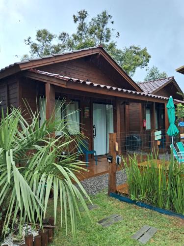 una casa de madera con porche y algunas plantas en Chalés praia do Rosa SC piscina comp, en Imbituba