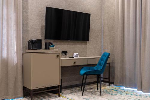 a desk with a blue chair and a television on a wall at Crona SPA Karpaty in Skhidnitsa