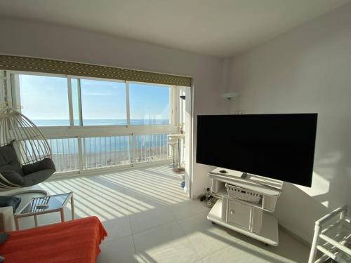 a living room with a flat screen tv and a balcony at Manhattan apartment in Empuriabrava