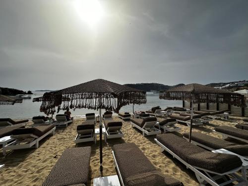 un mucchio di sedie e ombrelloni su una spiaggia di Agia Anna Beachfront Boutique a Paraga
