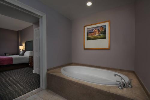a bathroom with a bath tub in a room with a bed at Marriott's Manor Club at Ford's Colony in Williamsburg