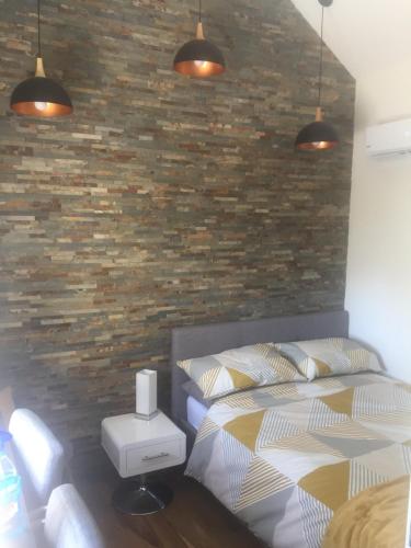 une chambre avec un lit et un mur de briques dans l'établissement Petit Luxe, à Mortroux