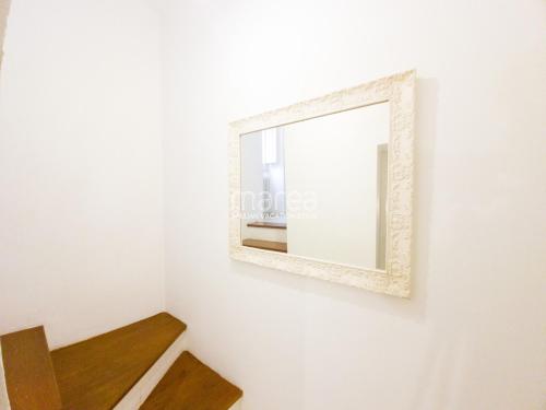 a mirror on a white wall with a wooden floor at La Torretta - Marea Stays Collection in Otranto