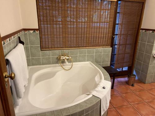 uma casa de banho com uma grande banheira branca num quarto em Cardoso Kitchen Bar & Lodge em Joanesburgo