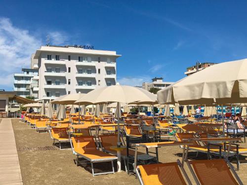 un montón de sillas y sombrillas en una playa en Hotel Caesar en Lido di Savio