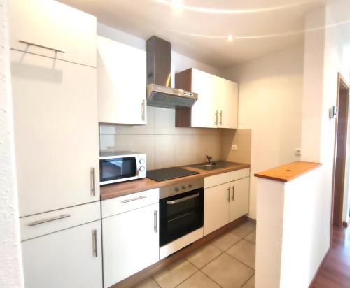 una cucina con mobili bianchi e un forno a microonde di #Lesgourmandises a Mulhouse