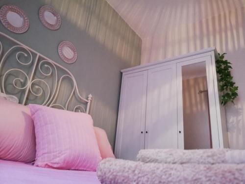 a bedroom with a pink bed and a white cabinet at Fillitsa's Sweet Home in Neos Marmaras