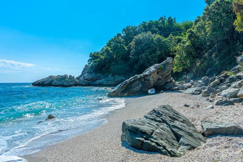a sandy beach with rocks and the ocean at SunRiseStudiosPapanero in Damouchari