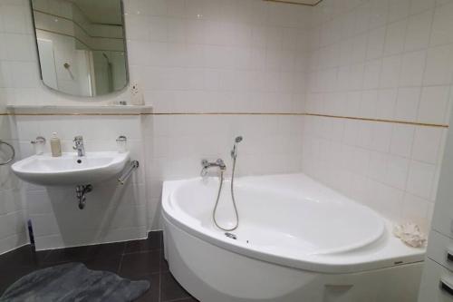 Baño blanco con lavabo, bañera y espejo en Ferienwohnung zentrale Lage, en Idar-Oberstein