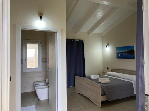 a bedroom with a bed and a bathroom with a toilet at Is Arenas Biancas Agriturismo in Teulada