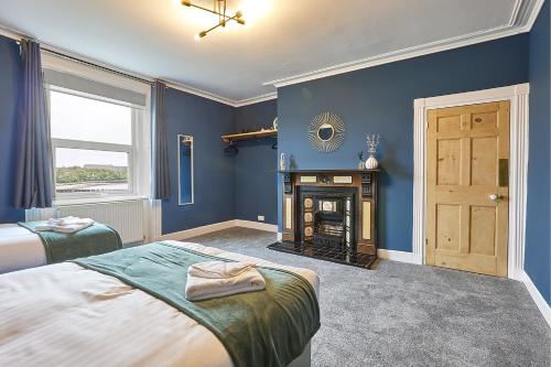 a blue bedroom with two beds and a fireplace at Arbeia - Properties Unique in South Shields