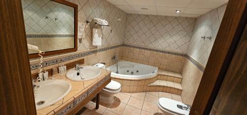 uma casa de banho com 2 lavatórios, uma banheira e um WC. em Castillo de Illueca em Illueca
