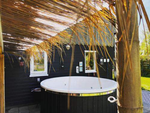 een badkamer met een groot bad in een zwart huis bij Het Wierhuis in Pieterburen