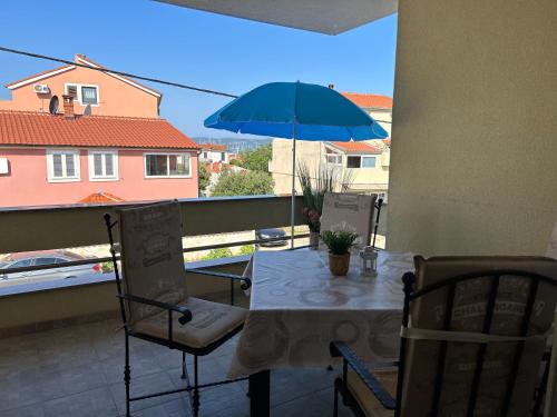 a table and chairs with a blue umbrella on a balcony at Apartment David in Biograd na Moru