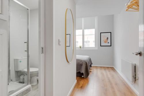 a white bathroom with a mirror and a bed at Stanley St Suites By GuestFirst in Liverpool