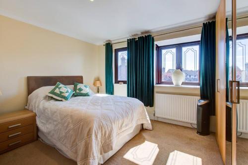 a bedroom with a bed and two windows at Serene Family Escape - Spacious, Near Thorpe Bay and Southend, Beaches & Amenities - Pass the Keys in Southend-on-Sea