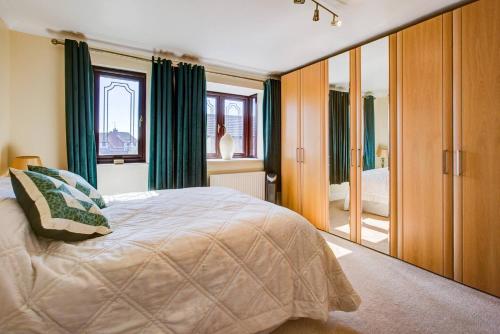 a bedroom with a bed with green curtains and a mirror at Beautiful house in Thorpe Bay in Southend-on-Sea