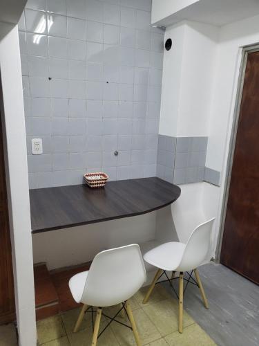 een keuken met twee witte stoelen en een tafel bij SLC San Martín 1 in San Luis