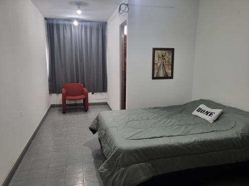 1 dormitorio con 1 cama y 1 silla roja en SLC San Martín 1 en San Luis