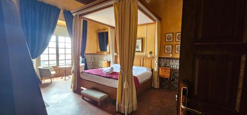 sypialnia z łóżkiem z baldachimem i oknem w obiekcie Castillo de Illueca w mieście Illueca