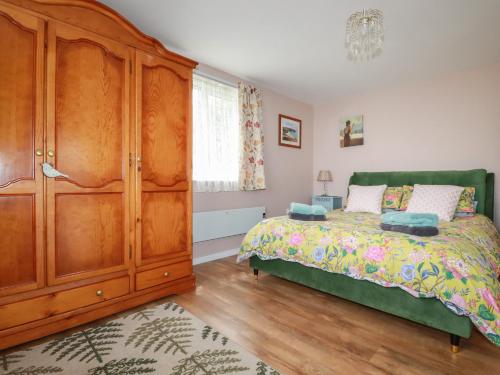 a bedroom with a bed and a wooden cabinet at Sunset Cottage in Tintagel